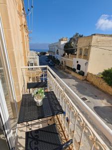 a balcony with tables and chairs on a city street at Ta'Roza Modern Apartment with Balcony & Distant Sea Views - Xaghra Gozo in Xagħra