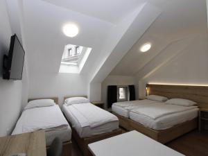 a room with three beds and a table and a window at Vila Mila in Sarajevo
