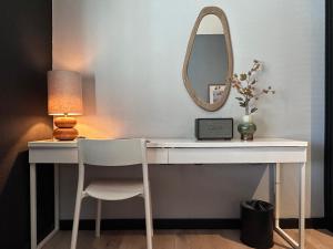 ein weißer Schreibtisch mit Lampe und Spiegel in der Unterkunft Hotel chic room in Heerlen