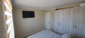 a bedroom with a tv on the wall and a bed at CABAÑA CON TINAJa in Guanaqueros