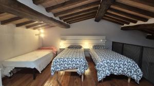 two beds in a room with wooden floors and wooden ceilings at Casetta di Ghino in Radicofani