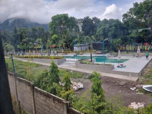 a swimming pool in a park with trees in the background at Penoria's lodge kubo in Mambajao