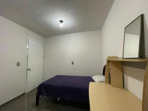 a small bedroom with a bed and a mirror at Oaxaca Express, comodidad y cercania al centro in Santa Lucía