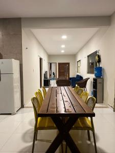 a wooden table with yellow chairs in a room at Casa Temporada Trairi in Trairi