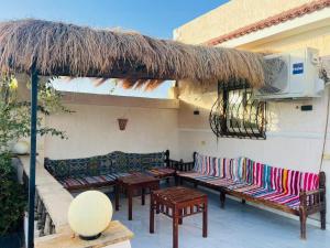 a patio with benches and a straw umbrella at شاليه الفهدي in Sphinx International Airport +9 photos