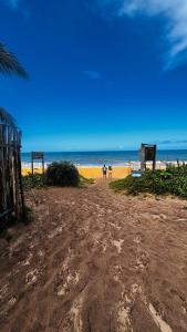 a sandy beach with two people walking on the beach at Kitnet charmosa a 4 min da praia in Porto Seguro