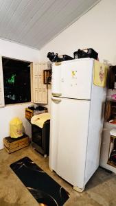 a kitchen with a white refrigerator in a room at Kitnet charmosa a 4 min da praia in Porto Seguro