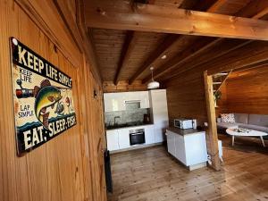a kitchen in a wooden cabin with a sign on the wall at Cottage relaxant au bord de l'eau in Bourbourg