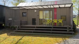 a small house with yellow chairs on the porch at HappyPlace - Kolpa PremiumMobileHome in Metlika