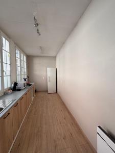 a kitchen with a white refrigerator and a wooden floor at Le Saint Sauveur - centre ville in Péronne