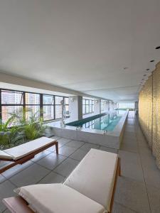 a large swimming pool in a building with benches and tables at FR1307B Estúdio alto padrão com cama king e garagem in Goiânia