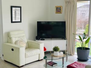 a living room with a white chair and a flat screen tv at ABC Homes Nedlands in Doncaster East