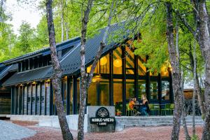 a building in the woods with people sitting at a table at Roble Viejo Lodge in Las Trancas