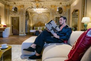 a man sitting on a couch reading a book at Palazzo Massimo Boutique Piazza Venezia in Rome