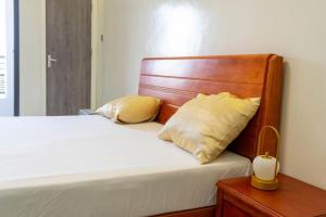 a bed with a wooden headboard and two pillows at Résidence Madior D2 in Dakar +1 photo