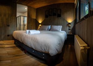 a bedroom with a large bed with wooden walls at Roble Viejo Lodge in Las Trancas