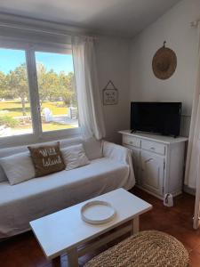 a living room with a couch and a tv and a window at Casa Mo in Cala en Bosc