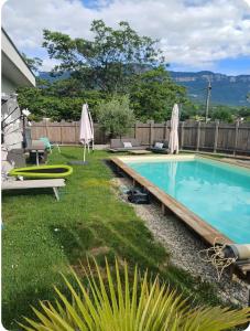 a swimming pool in a yard with umbrellas at Maison cosy in Grésy-sur-Aix