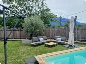 a backyard with a couch and an umbrella and a pool at Maison cosy in Grésy-sur-Aix