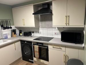 a kitchen with white cabinets and a black microwave at StaxBnB in London +63 photos
