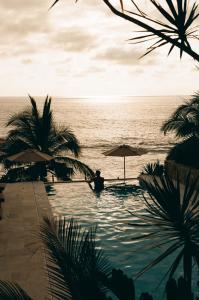 a man sitting in a swimming pool next to the ocean at La Joya Sayulita in Sayulita