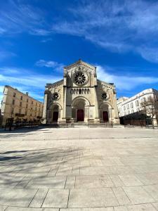 a large stone building with a clock on it at MataDoora in Nîmes