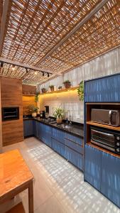 a large kitchen with blue cabinets and a table at Flat aconchegante em Juquehy! Com piscina! in Praia de Juquehy