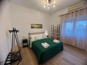 a bedroom with a green bed with towels on it at Le Camere di Don Nicó in Tarquinia