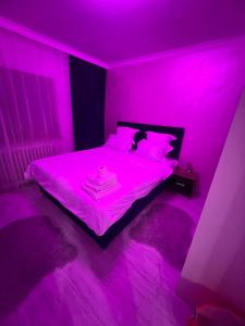 a bedroom with a bed with pink lights on it at city apartament in Oradea