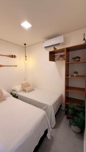 two beds in a room with white walls at Flat aconchegante em Juquehy! Com piscina! in Praia de Juquehy +22 photos