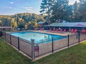 a fence around a swimming pool with red chairs at Lucky Trout Lodge in Heber Springs