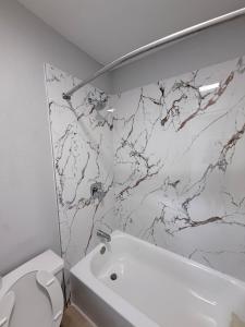 a bathroom with a white toilet and a marble wall at Relax Inn Bryan College Station in Bryan