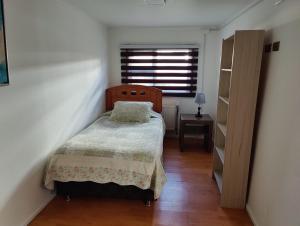 a small bedroom with a bed and a window at Casa amoblada en Punta arenas in Punta Arenas
