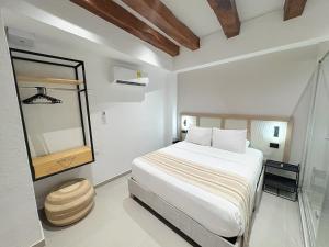 a white bedroom with a bed and a mirror at Casa Helena Getsemaní in Cartagena de Indias