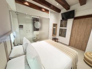 a bedroom with a large white bed and a tv at Casa Helena Getsemaní in Cartagena de Indias +53 photos