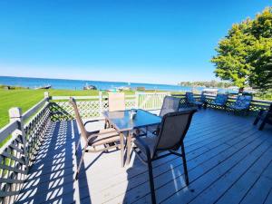 a deck with a table and chairs and the ocean at Oneida Lakeside Retreat in Bridgeport