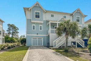 a large blue house with a palm tree in front of it at Salt & Pine in Pensacola