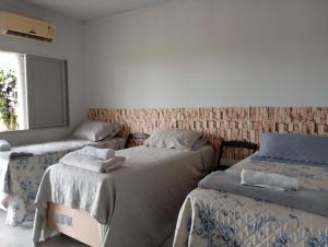 a room with three beds and a window at Pousada Venture Jalapao in São Félix do Tocantins