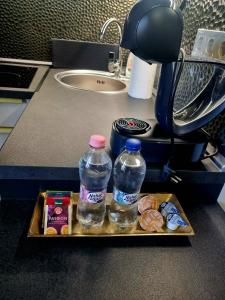 a tray with two bottles of water and donuts on a counter at MonDa apartman in Salgótarján
