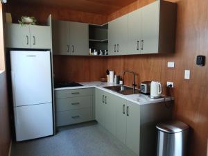 a kitchen with white cabinets and a white refrigerator at Harbour Heights Cabins in Athenree +13 photos