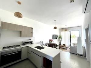 a white kitchen with a sink and a living room at Beachfront Paradise - Huge Pool, Ocean View & Surf in Cabarete