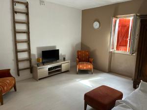 a living room with a television and a chair at GÎte à la ferme in Lalinde
