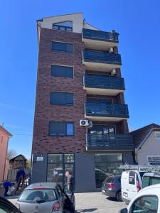 a tall brick building with cars parked in a parking lot at Apartman Park in Stara Pazova