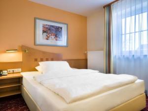 a large white bed in a room with a window at Mercure Hotel Ingolstadt in Ingolstadt +91 photos