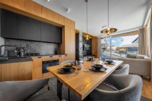 a kitchen and dining room with a wooden table and chairs at Salamandra Luxury Villas with Jacuzzi by BQQK in Kościelisko