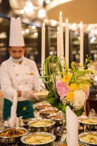 a chef in a kitchen behind a table with food at Sharz Hotel in Buraydah