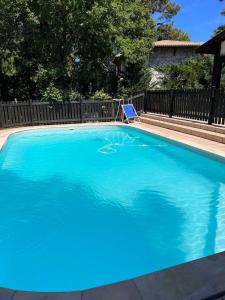 a swimming pool with blue water in front of a fence at Bask'aise o Pyla in La Teste-de-Buch