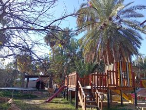 a playground with wooden play equipment and a palm tree at La tente tamaghza in Tamaghzah