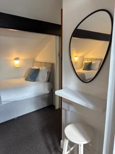 a bedroom with a mirror and a bed and a stool at The Dozy Deer in Windermere