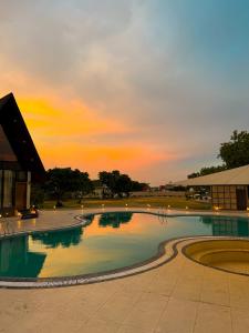 a swimming pool with a sunset in the background at Neora Farms in Simrol +11 photos
